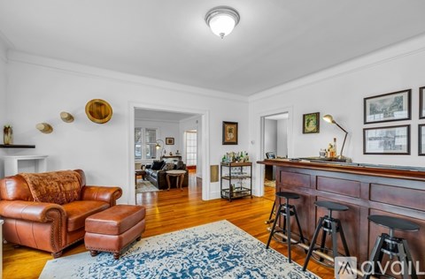 A living room with a brown leather couch and a blue patterned rug.