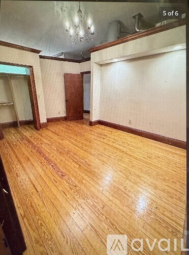 A room with wooden flooring and a chandelier.
