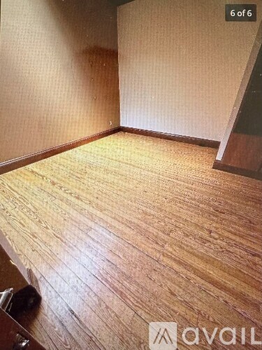 A room with wooden flooring and a wall with a door.