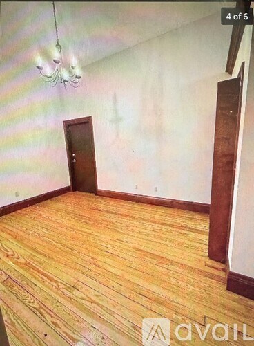 A room with wooden flooring and a chandelier.