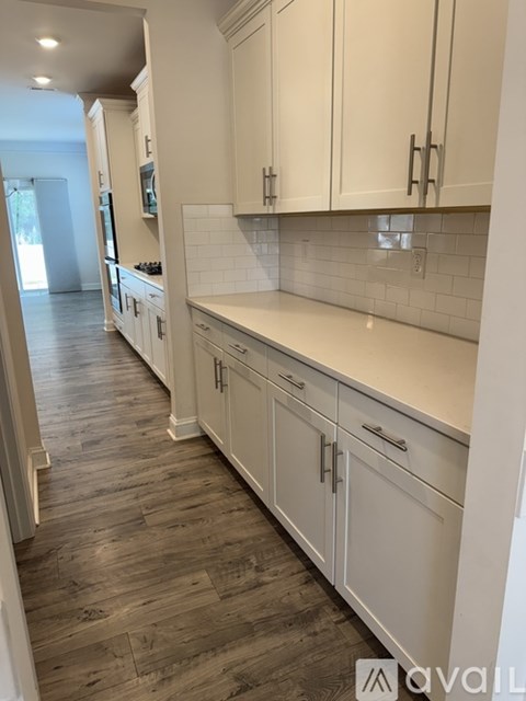 A kitchen with white cabinets and a wooden floor.