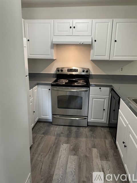 A kitchen with a stove top oven and white cabinets.