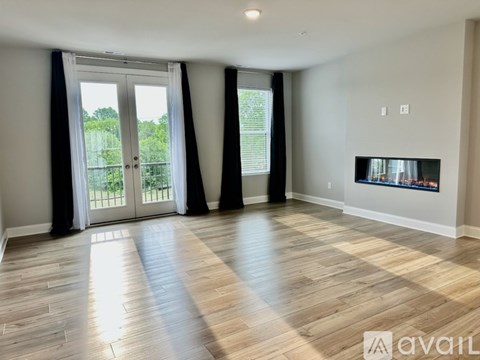 A living room with a wooden floor and a television on the wall.