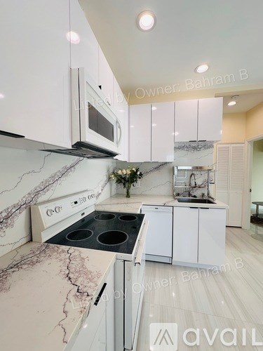 A kitchen with white cabinets and a marble countertop.