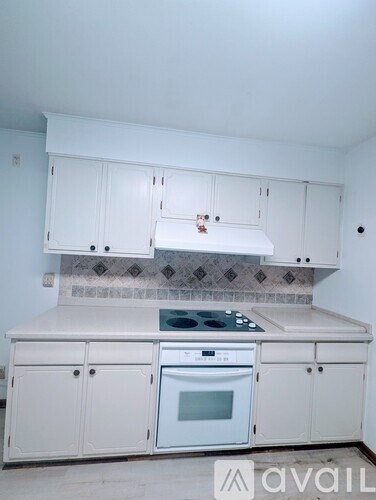 A kitchen with white cabinets and a tiled backsplash.