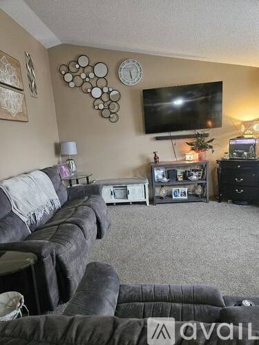 A living room with a grey couch and a television mounted on the wall.