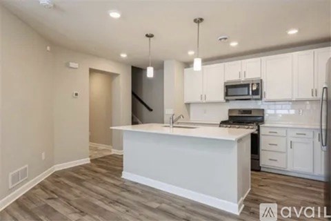 A kitchen with white cabinets and a wooden floor.