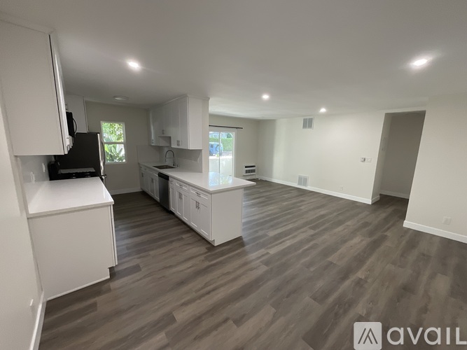 A spacious kitchen with white cabinets and a wooden floor.