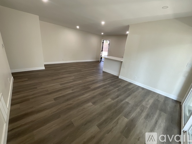 A spacious room with wooden flooring and white walls.