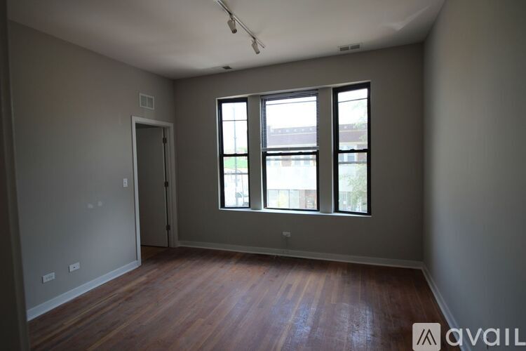 A room with wooden floors and a large window with a view of a parking lot.