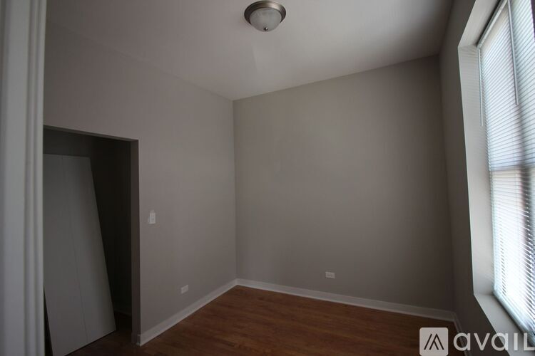 A room with a wooden floor and a window on the right side.