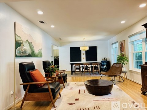 A living room with a black couch, a wooden coffee table, and a painting on the wall.