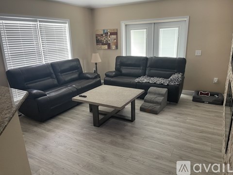 A living room with black leather furniture and a wooden coffee table.