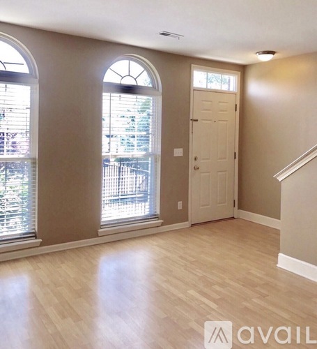 A room with a door, a window with blinds, and a staircase.