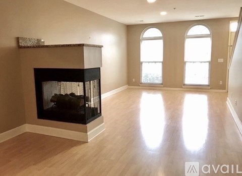 A large, empty room with a fireplace and wooden floors.