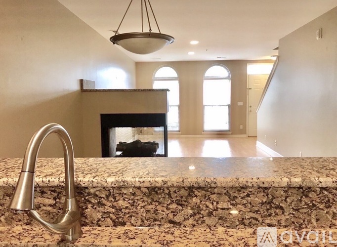 A kitchen counter with a sink and a fireplace in the background.