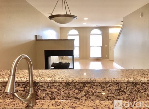 A kitchen counter with a sink and a fireplace in the background.