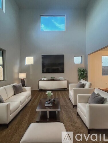 A living room with white furniture and a flat screen TV mounted on the wall.