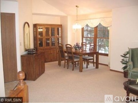 A living room with a wooden cabinet, a dining table with chairs, and a potted plant.