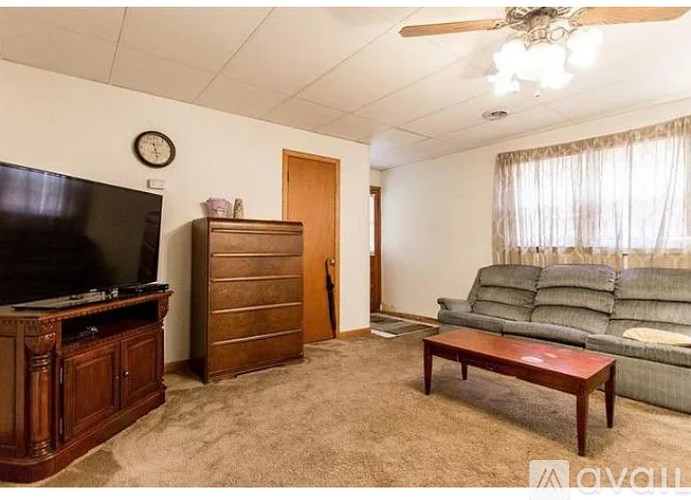 A living room with a television, a couch, a coffee table, and a ceiling fan.