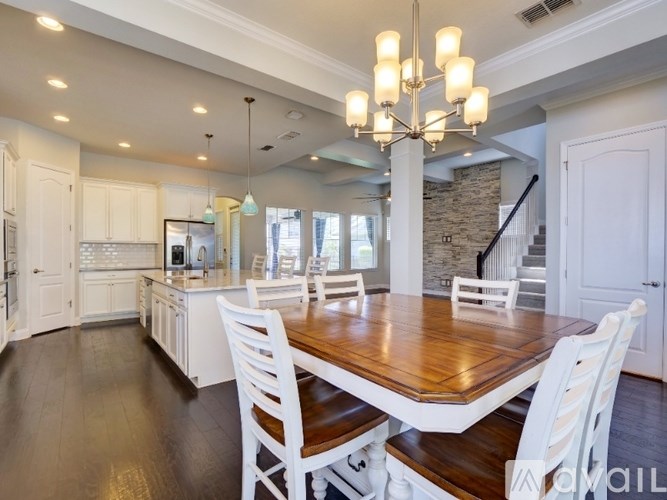 A dining room with a wooden table and white chairs.