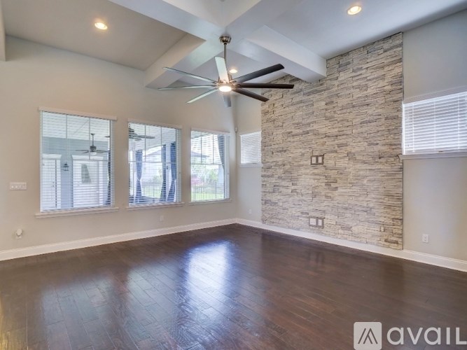 A spacious room with a stone wall and a ceiling fan.