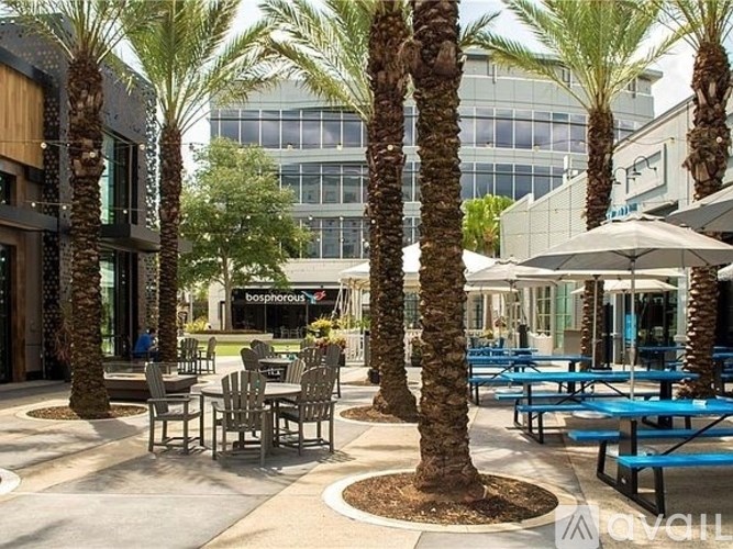 A patio with tables and chairs surrounded by palm trees.