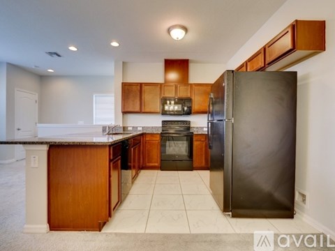 A kitchen with a black refrigerator and wooden cabinets.