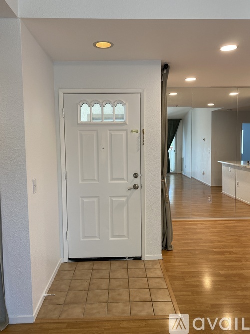 A white door with a glass window is in a room with wooden floors.