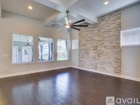 A spacious room with a stone wall and a ceiling fan.