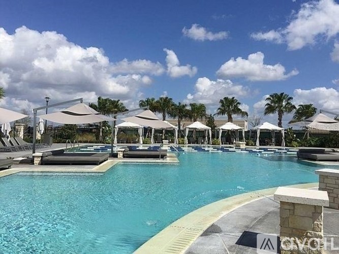 A large outdoor swimming pool surrounded by lounge chairs and umbrellas.