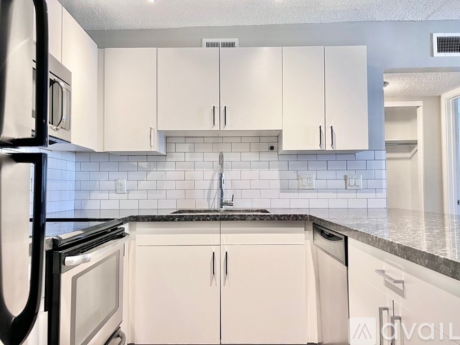 A kitchen with white cabinets and black appliances.