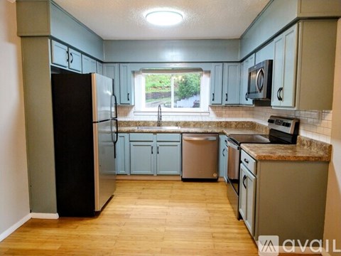 A kitchen with a black fridge and wooden floors.