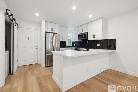 A kitchen with white cabinets and a black and white backsplash.