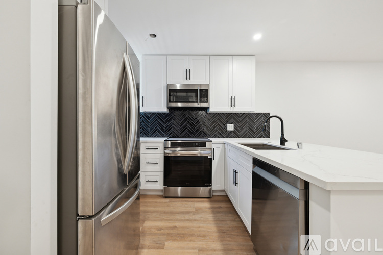A modern kitchen with a stainless steel refrigerator and white cabinets.