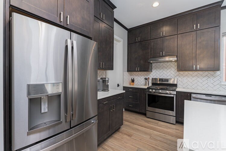 A modern kitchen with dark wood cabinets and stainless steel appliances.