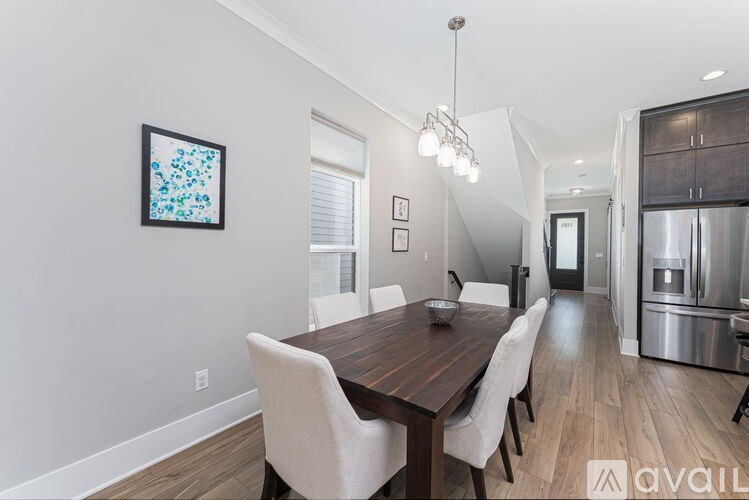 A modern dining room with a wooden table and white chairs.