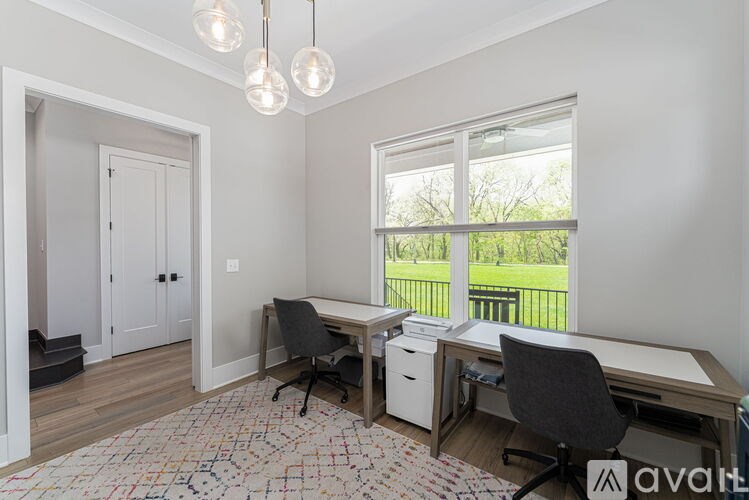 A room with a desk, chairs, and a window overlooking a green area.