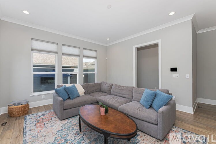 A living room with a grey couch, a coffee table, and a rug.
