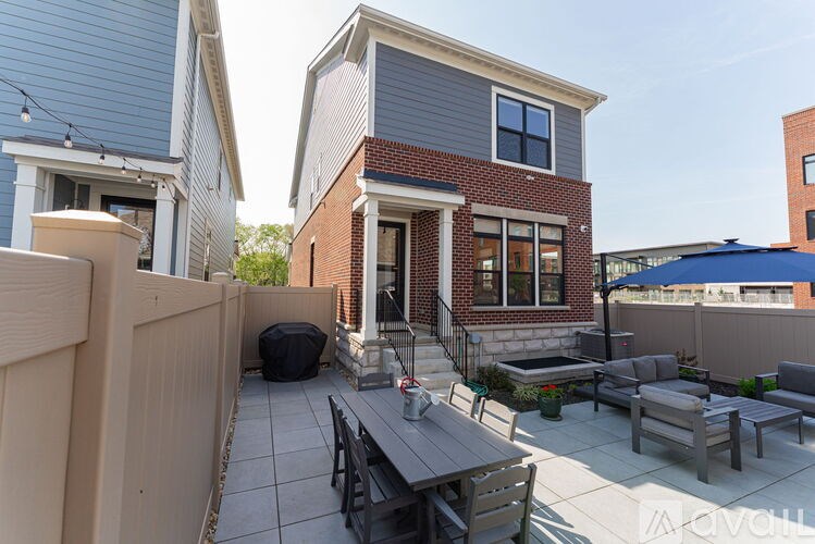 A patio with a table and chairs is in front of a brick house.
