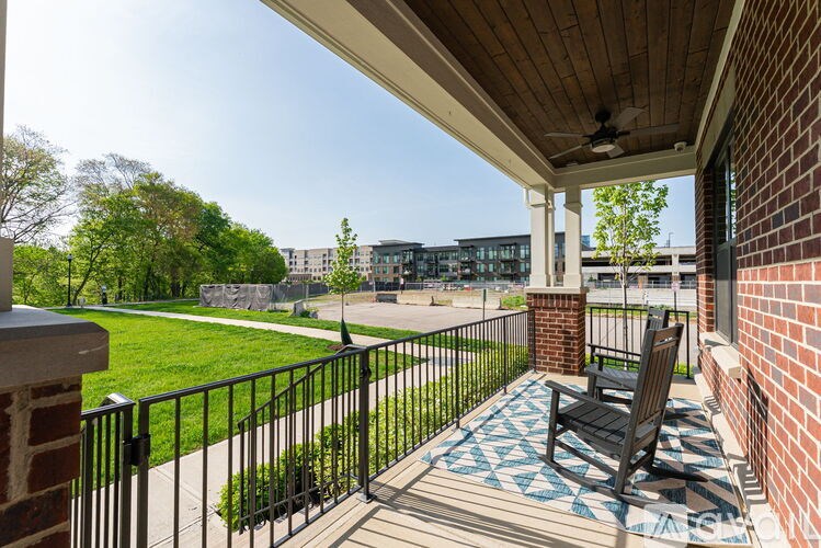 A balcony with a black metal railing and a black chair on a blue and white patterned rug.