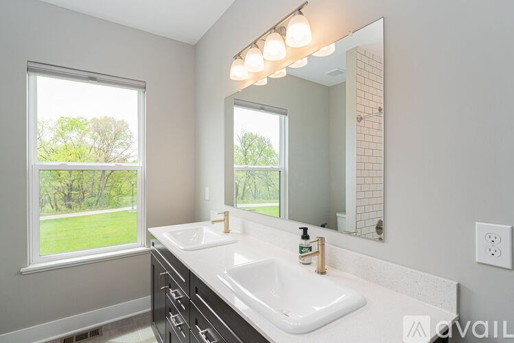 A bathroom with a large mirror, a window, and a sink.