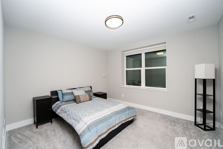 A bedroom with a bed, nightstand, and window.