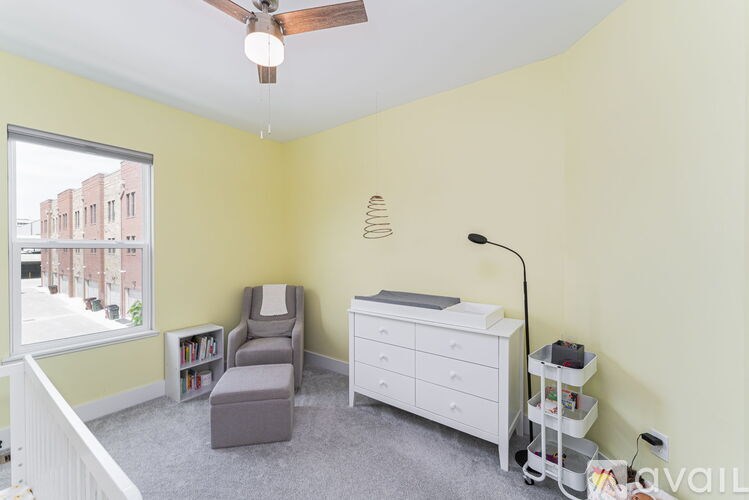 A room with a white dresser and a grey chair.
