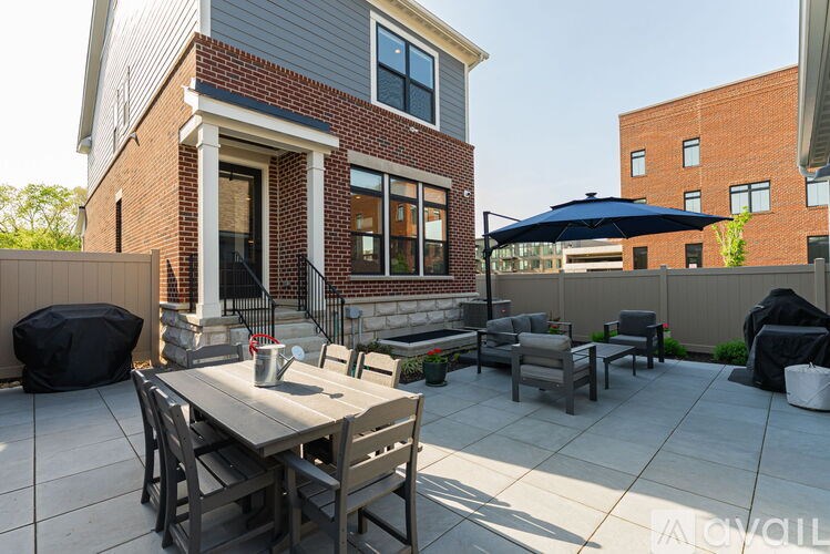 A patio with a table and chairs is in front of a brick house.