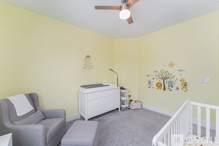 A baby room with a crib, chair, and wall decals.
