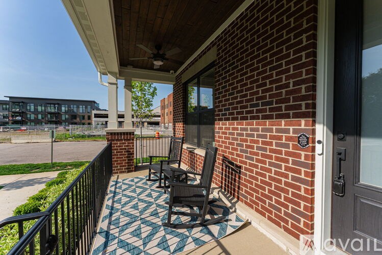 A balcony with a black rocking chair and a patterned rug.
