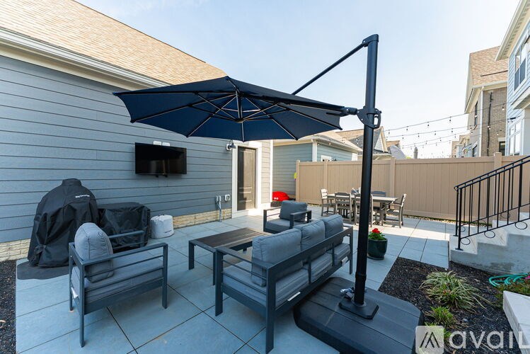 A patio with a black umbrella and furniture.