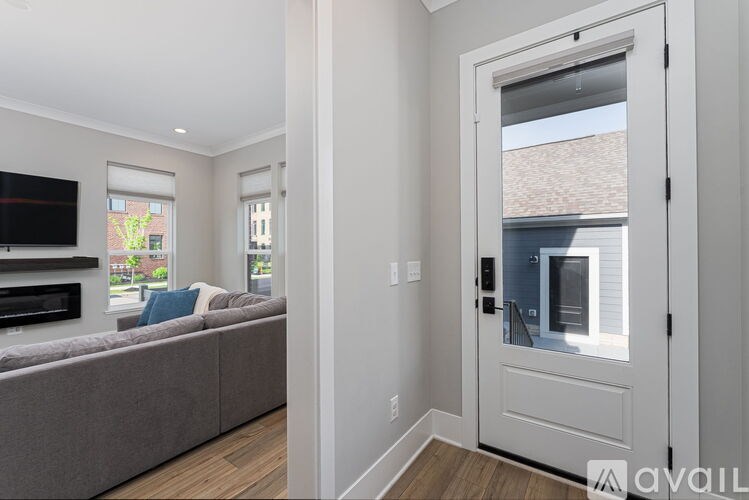 A living room with a grey couch and a flat screen TV mounted on the wall.