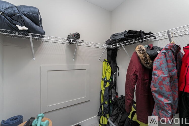 A closet with a white shelf and clothes hanging on it.